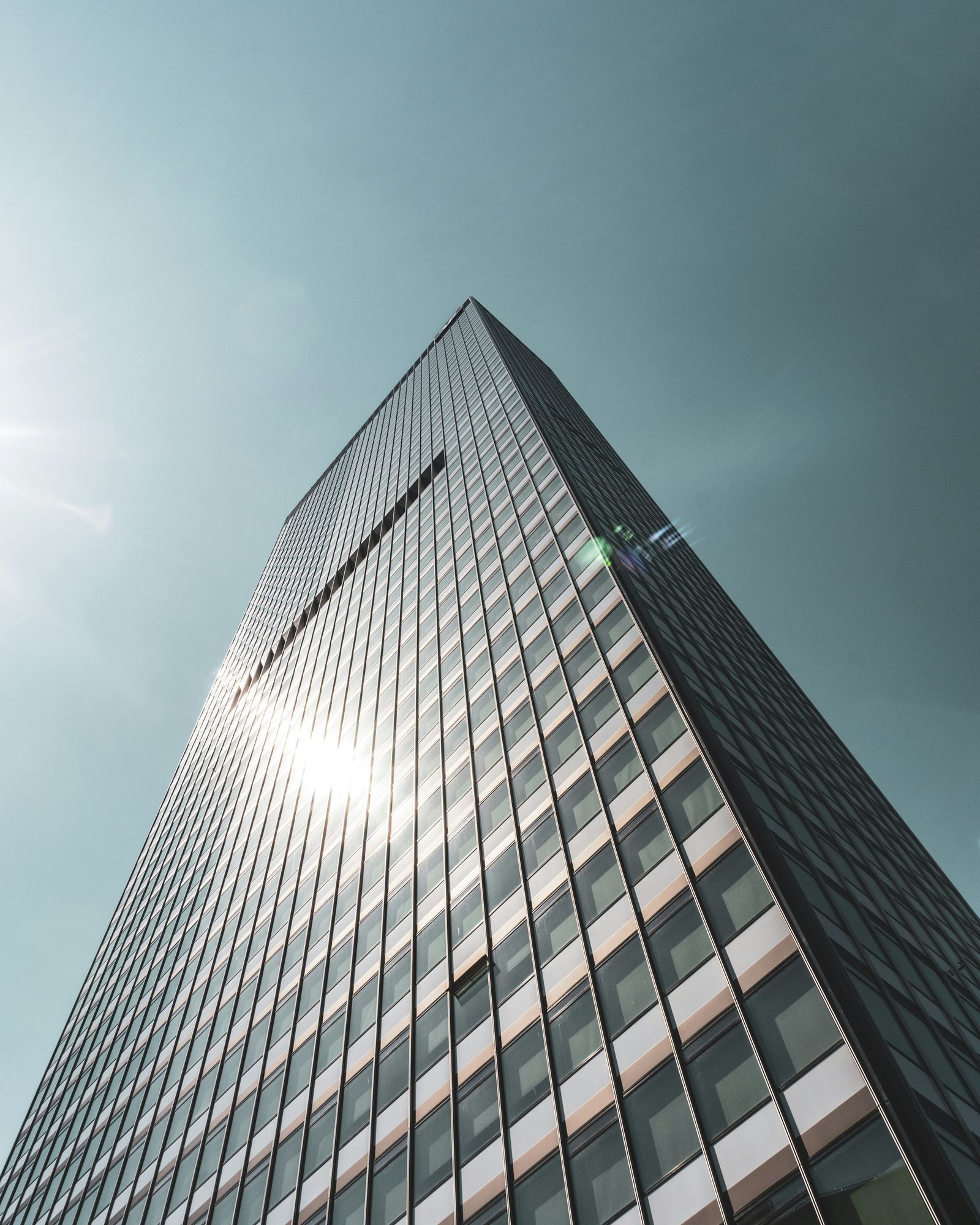 Glass office tower rising against a pale sky